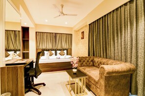Une chambre d’hôtel avec un lit, un canapé, un bureau et une chaise.