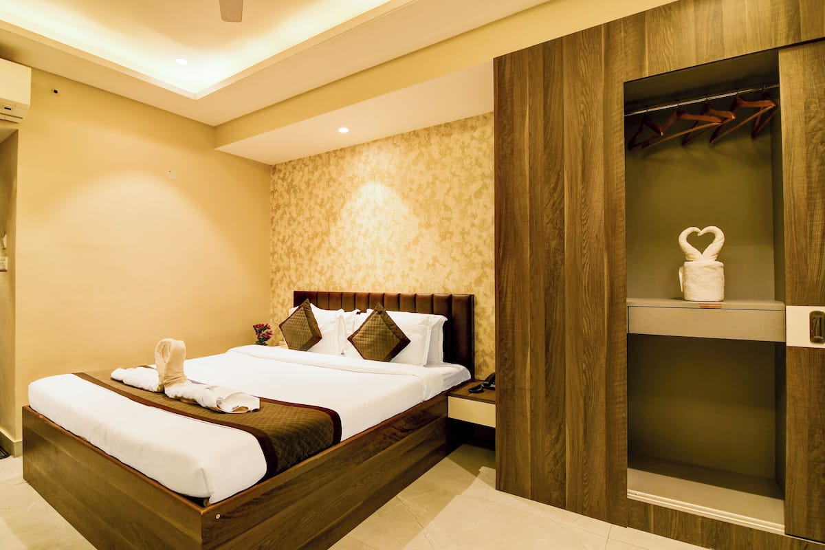 Habitación de hotel con una cama grande, cabecero de madera, una mesita de noche y un armario con espejo.