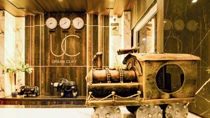 A vintage steam locomotive in a lobby with clocks and a sign reading "URBAN CLIFF".