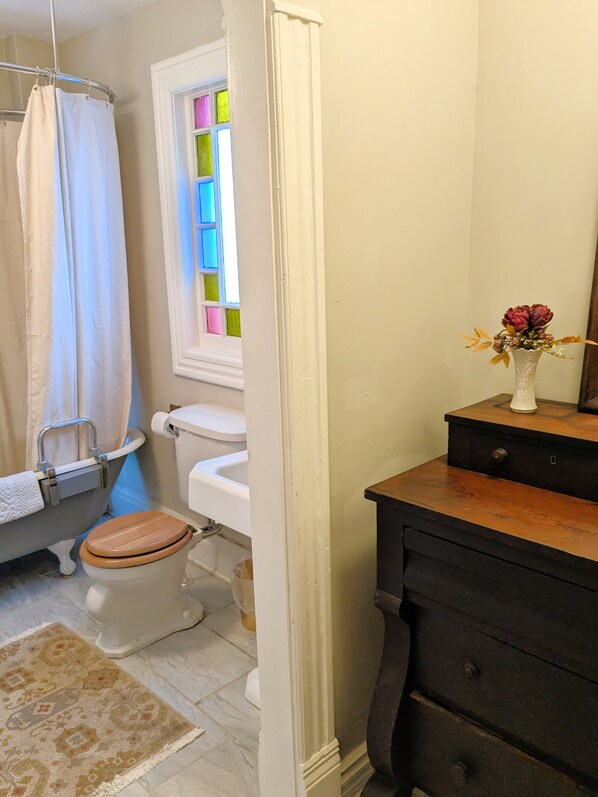 A bathroom with a bathtub, toilet, and a wooden vanity.