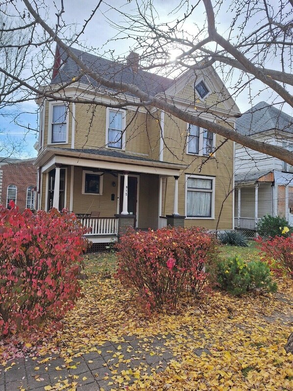 Une maison à deux étages avec un porche à l’avant, une boîte aux lettres bien visible et le numéro « 915 » sur le poteau.