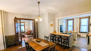 Una cocina amplia con una isla de madera, un comedor con una mesa grande y sillas, y vistas al salón.