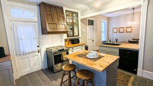 Una cocina moderna con una isla central, taburetes de bar, horno empotrado y lavavajillas.