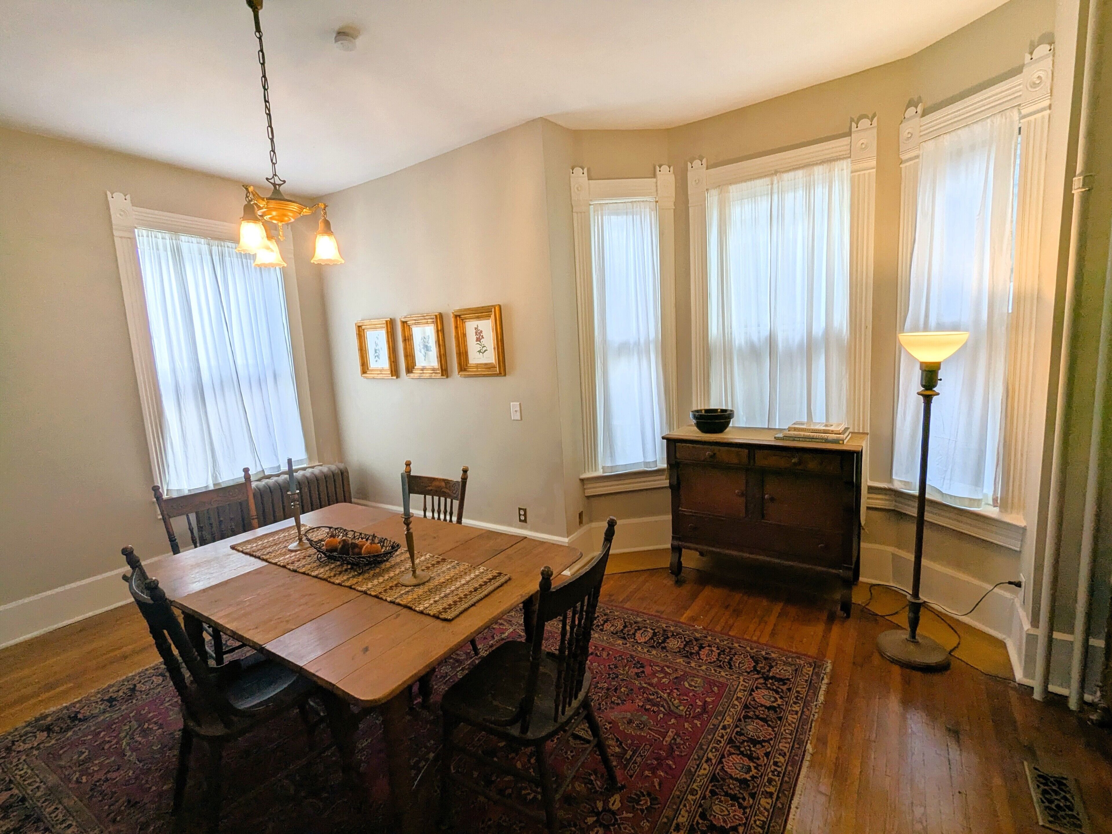 A dining area with a wooden table, chairs, a rug, and a chandelier.