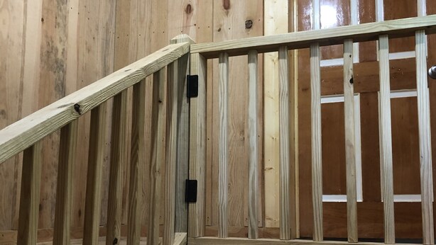 A wooden staircase with a handrail, leading to a door with a white frame. - Charming studio apartment in Whiteville (Whiteville)