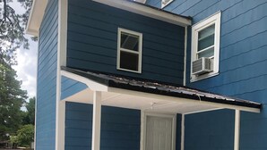 A two-story house with a blue exterior and white trim. - Charming studio apartment in Whiteville (Whiteville)