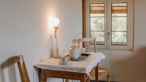 Un comedor con una mesa para dos, una lámpara y una ventana con persianas.