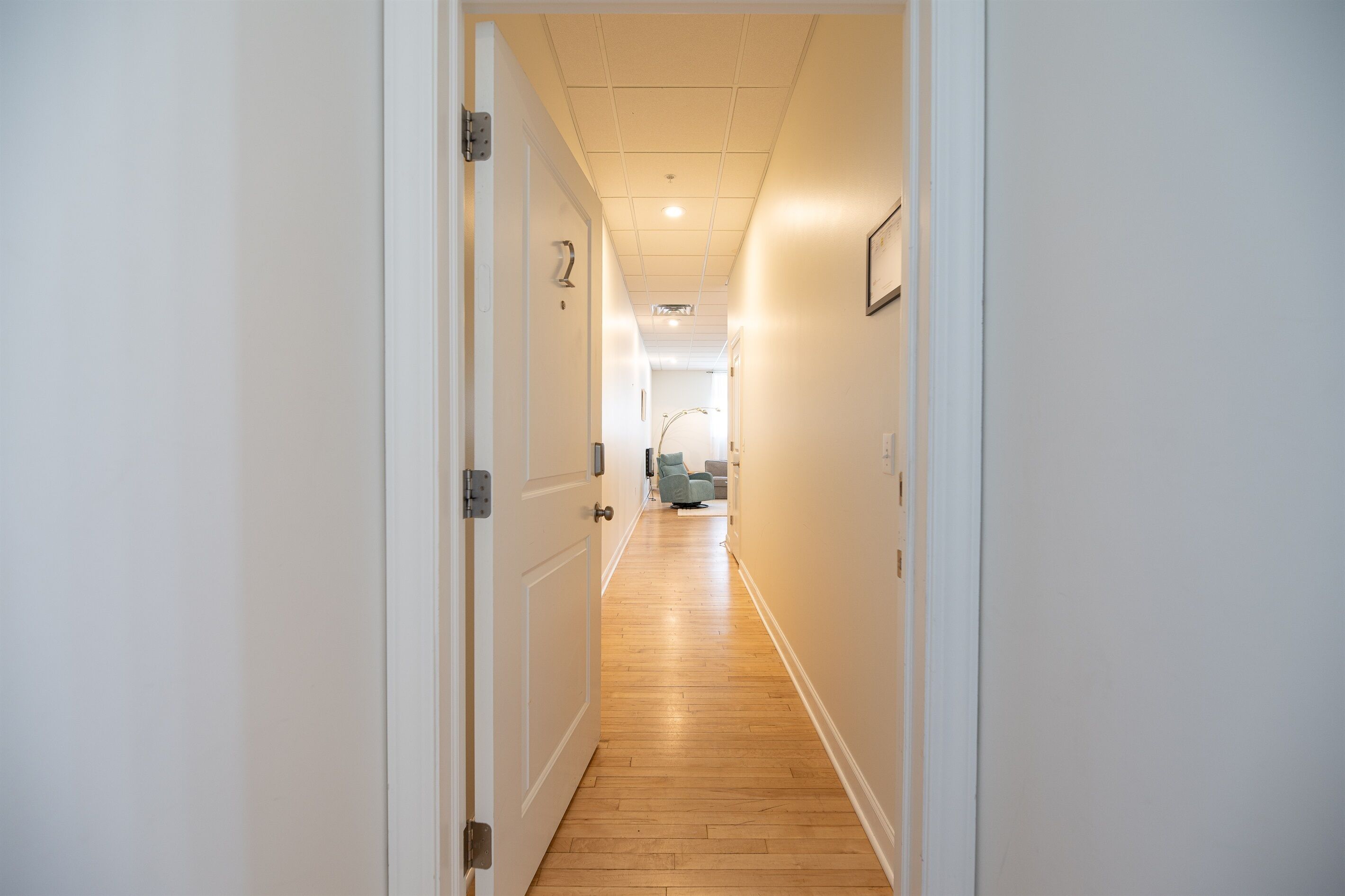 Un couloir étroit avec un plancher en bois et des murs blancs.