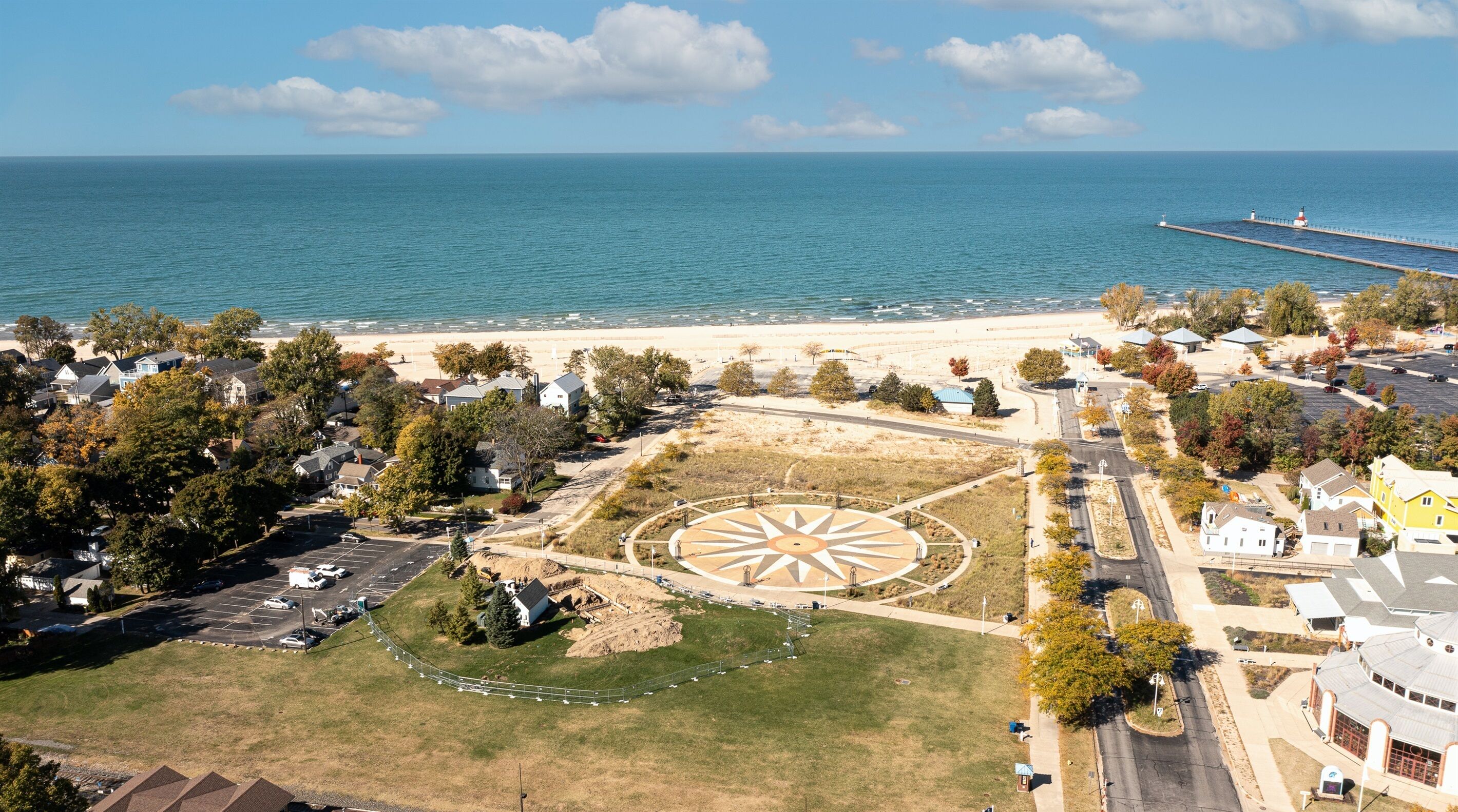 Un pueblo costero con un faro, playa y un parque central de diseño en forma de estrella.