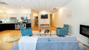 En moderne stue med en grå sofa, et glasbord og et fjernsyn monteret på væggen.