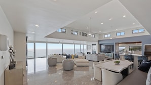 A spacious living area with a large window overlooking the sea, a modern kitchen, and a dining area. - Encinitas Shores - Beachfront, Ocean View & Patio (Encinitas)