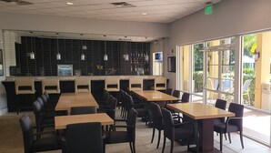 Un restaurant avec des tables et des chaises, un jeu de fléchettes BullShooter et une vue sur l’extérieur.