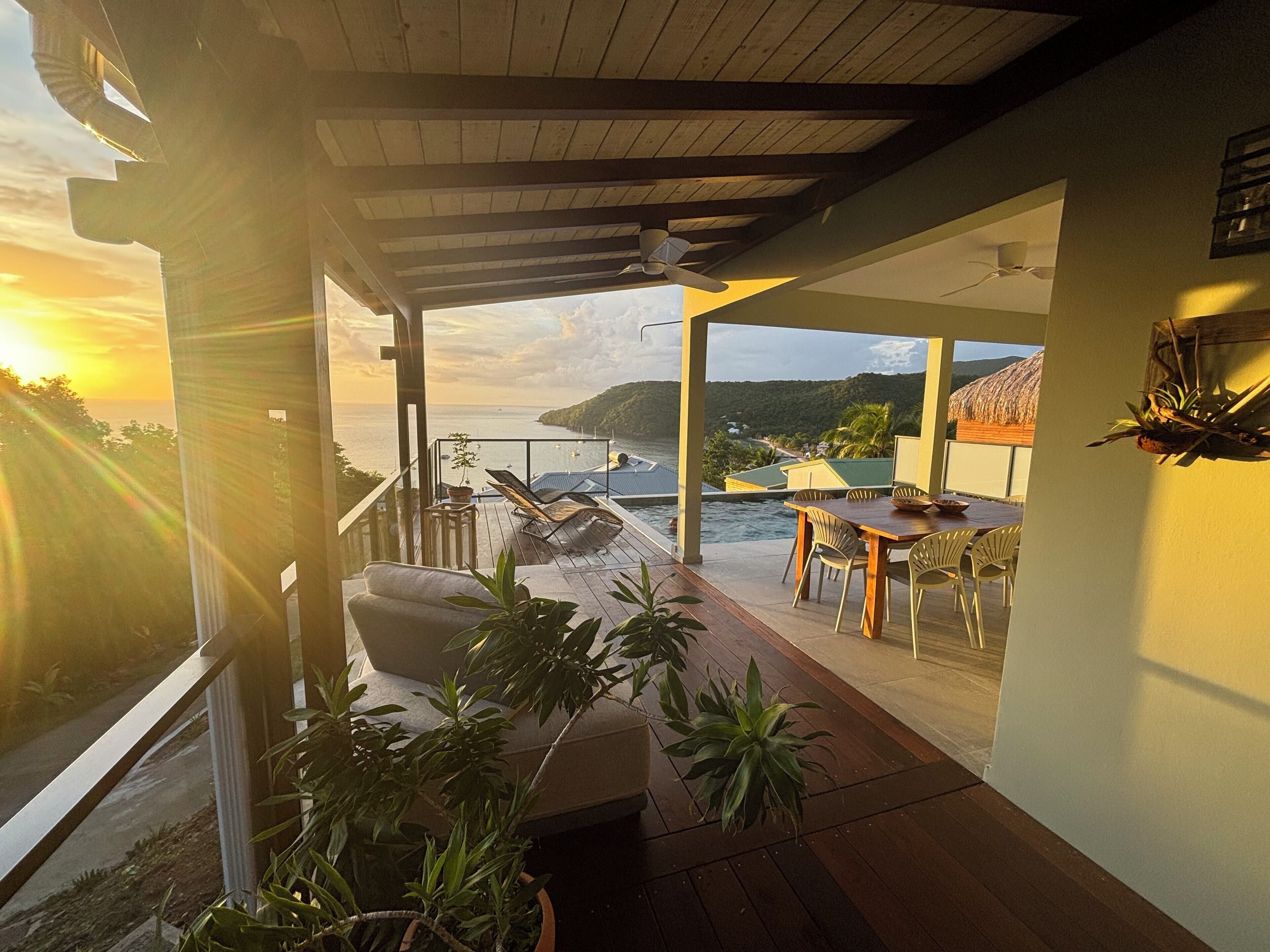 A covered outdoor area with a wooden deck, lounge chairs, and a table.