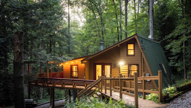 Een chalet met terras en overdekte veranda, omgeven door bos.