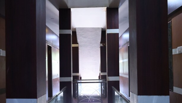 Un couloir doté d’une rambarde en verre, d’une main courante en métal et d’un plafond laissant apparaître les poutres et les tuyaux.