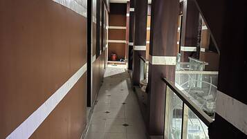 A corridor with tiled flooring, wooden paneling, and glass railings.
