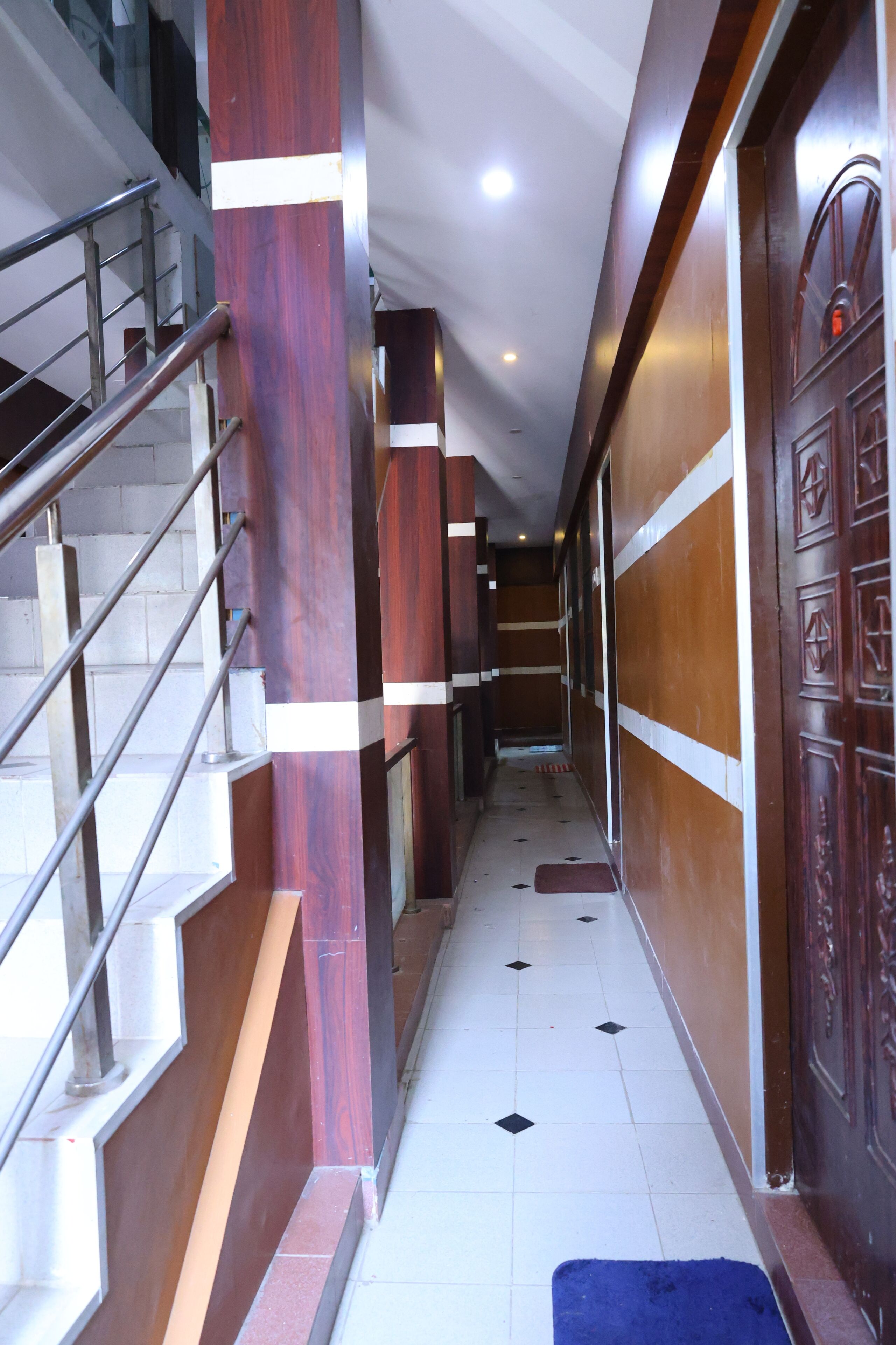 A corridor with a staircase on the left, wooden columns, and a door on the right.