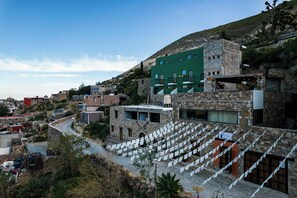 A stone building with a green facade and multiple balconies, surrounded by a hilly landscape. - Villa Mosaico (Real de Catorce)