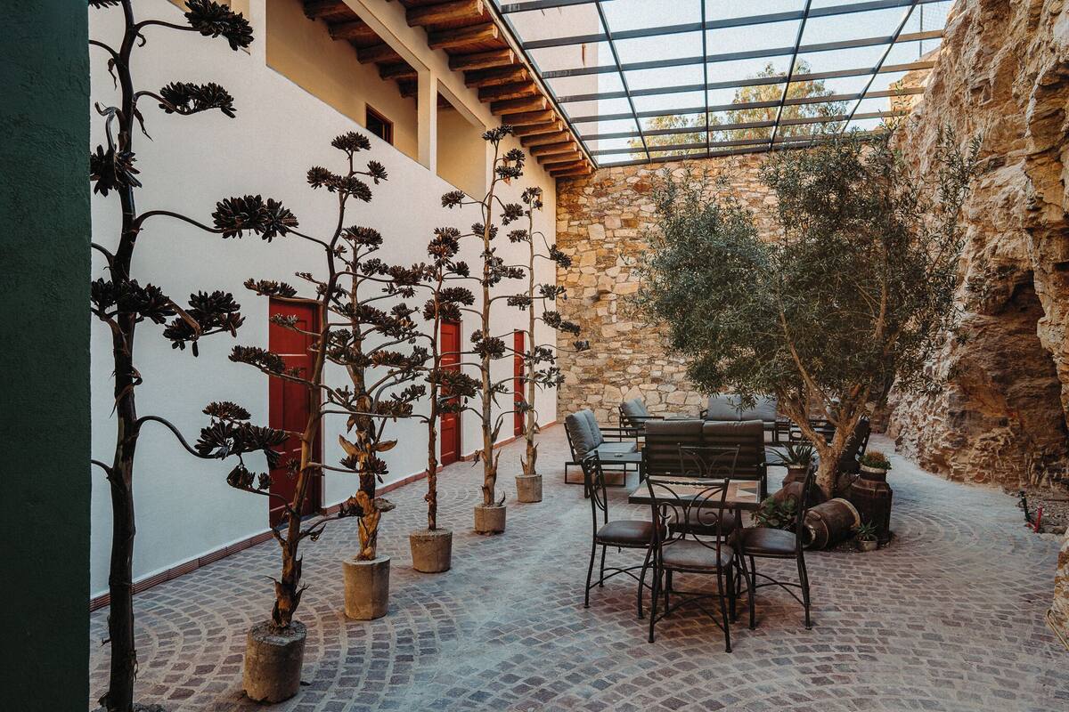 A courtyard with stone walls, potted plants, and outdoor seating.