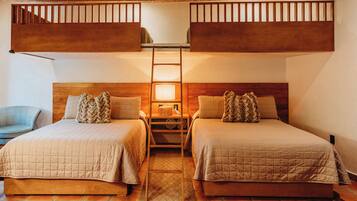Una habitación con dos camas, una escalera, una silla y una mesita de noche con lámpara.
