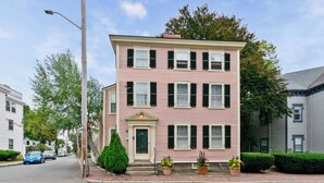 A pink two-story building with a green door and multiple windows. - Spacious 1BR on Salem Common l Steps to Downtown l Fenced in Yard + Parking (Salem)