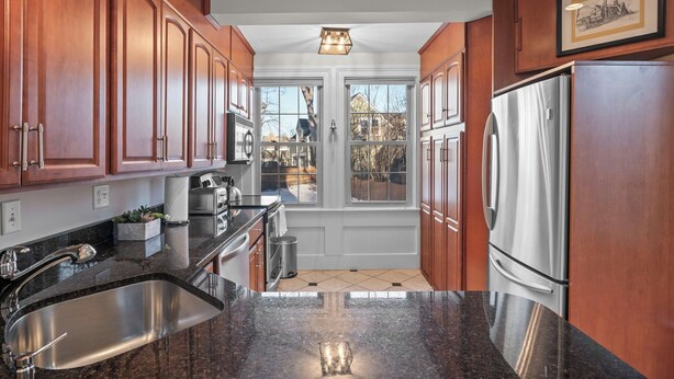 A kitchen with wooden cabinets, stainless steel appliances, and a view to the outside. - Spacious 1BR on Salem Common l Steps to Downtown l Fenced in Yard + Parking (Salem)