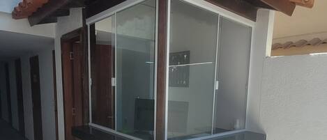A corner room with a glass enclosure, a tiled floor, and a wooden door.