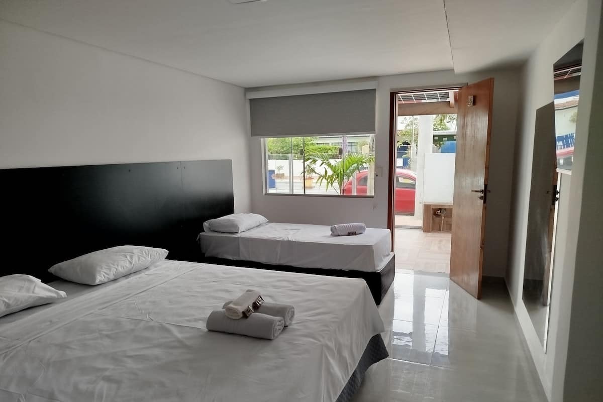 A hotel room with two beds, a large window, and a view of the outside.