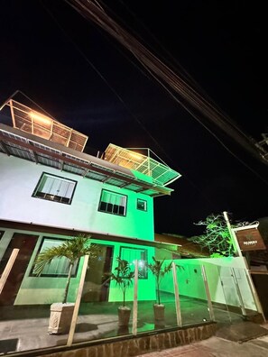 Un bâtiment à deux étages, doté d’une façade illuminée de lumière verte et d’une structure sur le toit.