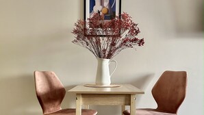 A dining table with two chairs, a vase with dried flowers, and a framed artwork on the wall. - Cozy studio with WiFi and AC in center of Almaty (Almaty)