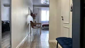 A hallway with wooden flooring, a mirror, a bench, and a door leading to a bedroom. - Cozy studio with WiFi and AC in center of Almaty (Almaty)