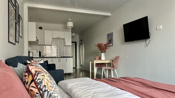 A modern bedroom with a bed, a desk, and a TV. - Cozy studio with WiFi and AC in center of Almaty (Almaty)