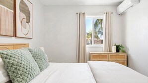 A bedroom with a bed, a bedside table, a window with curtains, and wall art. - NEW Tranquil Escape - Hot Tub, BBQ, Near LA & Disney (Covina)