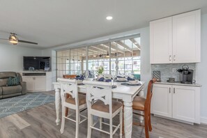 Enjoy a spacious living area with a dining table for four, a kitchen with white cabinets, and a comfortable seating area.