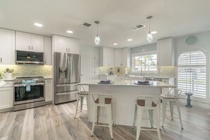 Enjoy cooking in this well-equipped kitchen with stainless steel appliances, a central island, and a large window with blinds.