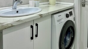 Een moderne badkamer met een wastafel, spiegel en wasmachine.