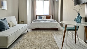 Een moderne hotelkamer met een bed, een bank, een klein tafeltje en een televisie.