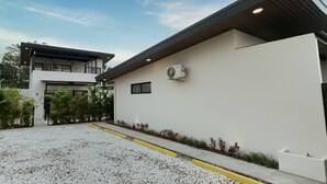 En moderne bygning med fladt tag, stor aircondition-enhed monteret på væggen, og en grusindkørsel med gule kanter.