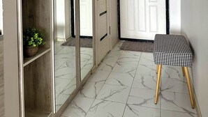 Un pasillo con un armario espejado, una puerta con teléfono y un banco.