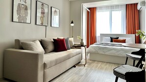 Habitación de hotel moderna con sofá, cama, escritorio y silla. Hay tres cuadros en la pared.