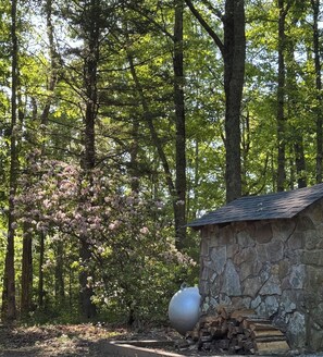 A stone cabin with a metal pot and firewood.