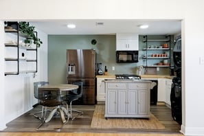 Uma cozinha compacta com área de refeições, forno embutido, micro-ondas e pia.