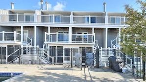 A multi-story residential building with balconies, a gated entrance, and a covered outdoor area. - Spacious, family friendly 4-bedroom condo with pool in charming Dewey Beach!! (Dewey Beach)