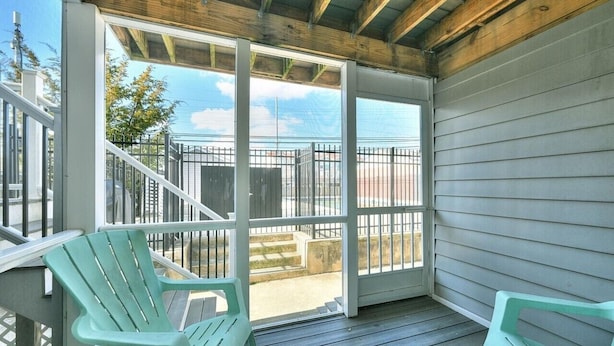 A covered porch with a view of a fenced yard, two green chairs, and a wooden ceiling. - Spacious, family friendly 4-bedroom condo with pool in charming Dewey Beach!! (Dewey Beach)