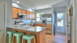 A modern kitchen with wooden cabinets, stainless steel appliances, and a granite countertop. - Spacious, family friendly 4-bedroom condo with pool in charming Dewey Beach!! (Dewey Beach)