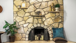 Una chimenea de piedra con un estante superior que sostiene objetos decorativos.