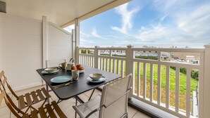 A balcony with a table set for dining, white railings, and a view of a cityscape. - Ty Enogat- Proche de la plage, garage privé (Dinard)