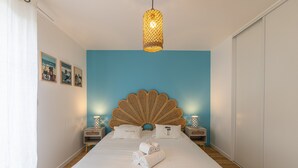 A bedroom with a large bed, a rattan headboard, and a hanging light fixture. - Ty Enogat- Proche de la plage, garage privé (Dinard)