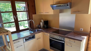Una cocina equipada con lavavajillas, horno y estufa integrada. Se observa una ventana con vista a zonas verdes.