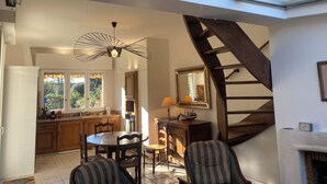 A modern interior with a skylight, a dining area, a kitchen, and a staircase.